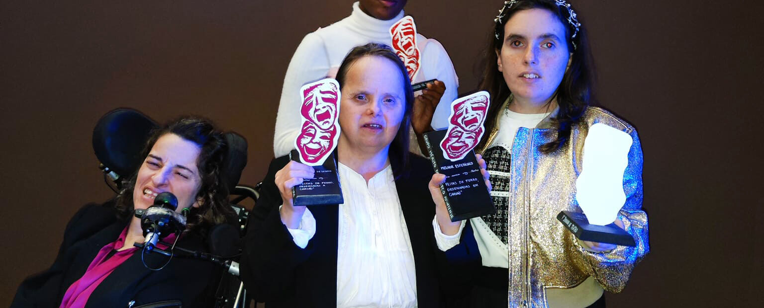 Quatro pessoas na imagem. Três delas seguram nas mãos quatro troféus.