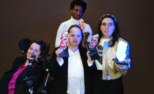 Quatro pessoas na imagem. Três delas seguram nas mãos quatro troféus.
