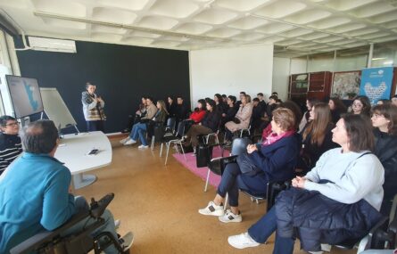 Sala interior de reunião com cerca de três dezenas de pessoas sentadas. Estão a ouvir outra pessoa que, de pé, faz uma apresentação oral.