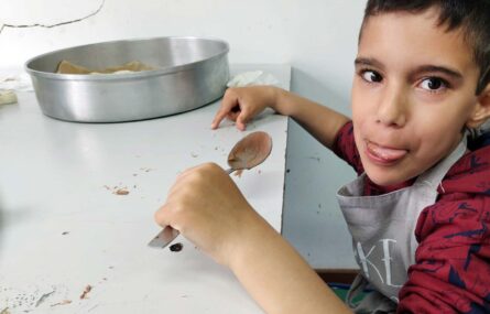 Uma criança segura uma colher com o que aparenta ser mousse de chocolate.