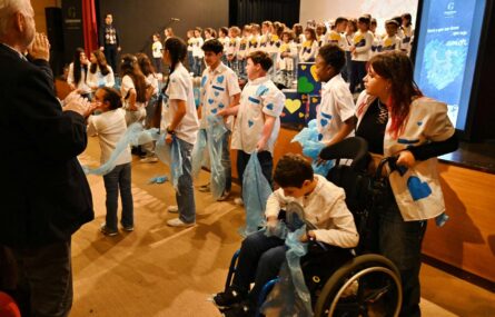 Várias dezenas de crianças e jovens alinhados junto (e em cima) de um palco. À esquerda são visíveis algumas pessoas a aplaudir.