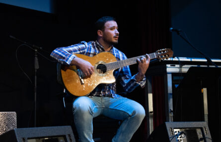Plano focado de uma pessoa com guitarra.