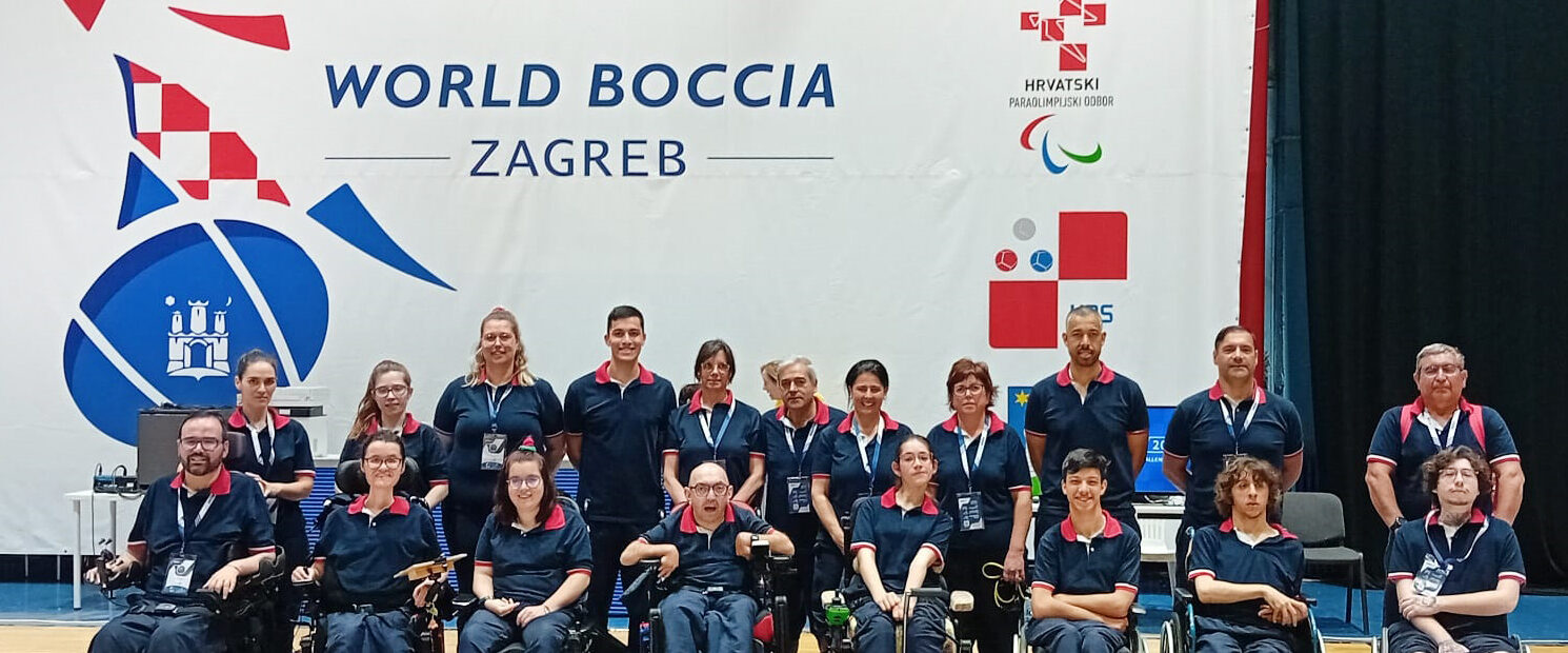 Fotografia da Seleção Nacional de Boccia. Aparecem, alinhadas, 19 pessoas (em pavilhão interior e junto de um cartaz gigante com o grafismo do World Boccia Zagreb).