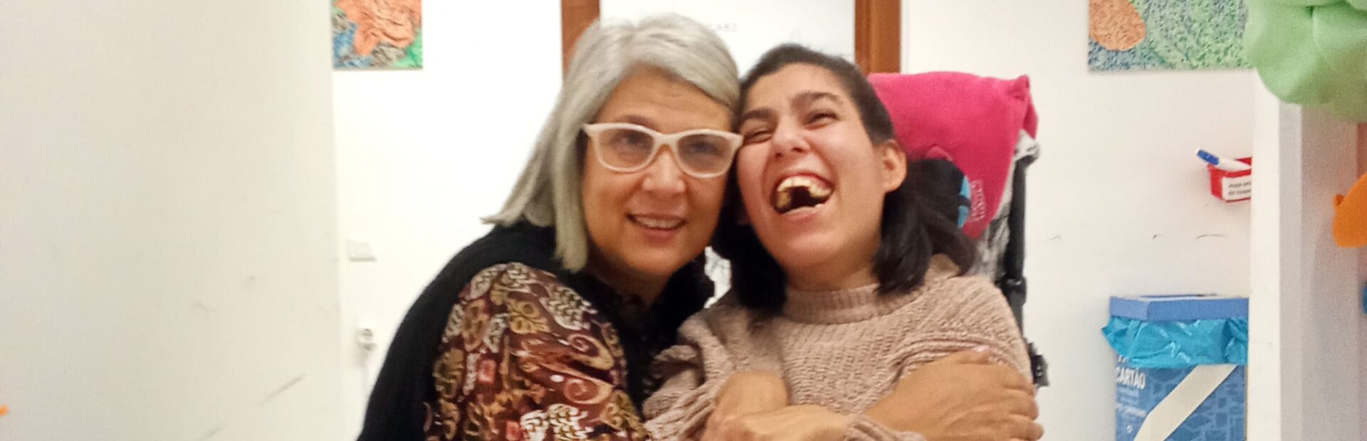 Fotografia de duas pessoas, sorridentes e abraçadas.