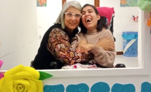 Fotografia de duas pessoas, sorridentes e abraçadas.