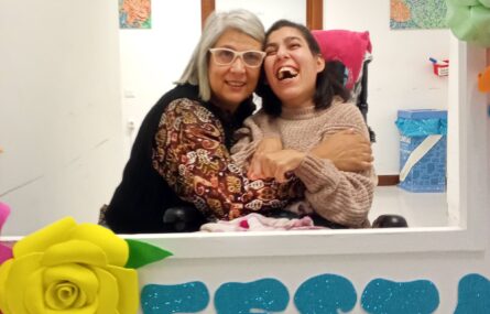 Fotografia de duas pessoas, sorridentes e abraçadas.