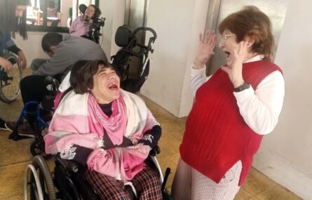 Em primeiro plano duas pessoas claramente sorridentes. Mais ao fundo outras pessoas.