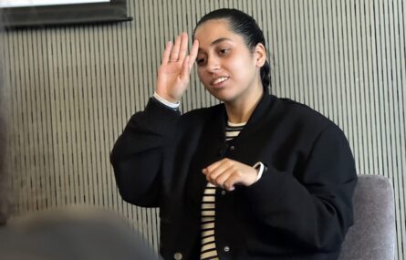 Pessoa sentada a gesticular (aparentemente e usar Língua Gestual Portuguesa).