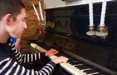 Uma pessoa com ar compenetrado aparenta estar a tentar tocar uma qualquer música num piano.
