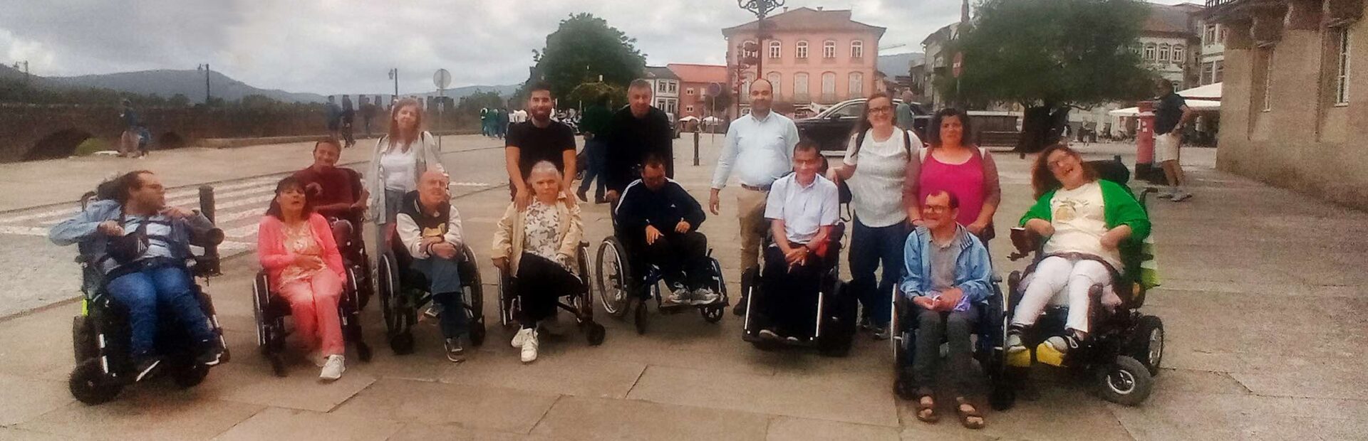 Fotografia de grupo com 15 pessoas (em zona exterior junto a alguns edifícios).