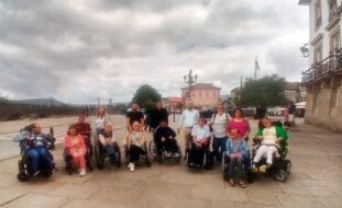 Fotografia de grupo com 15 pessoas (em zona exterior junto a alguns edifícios).