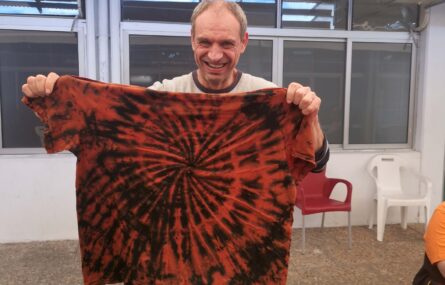uma pessoa a sorrir segura uma t-shirt, colorida (preta e laranja)