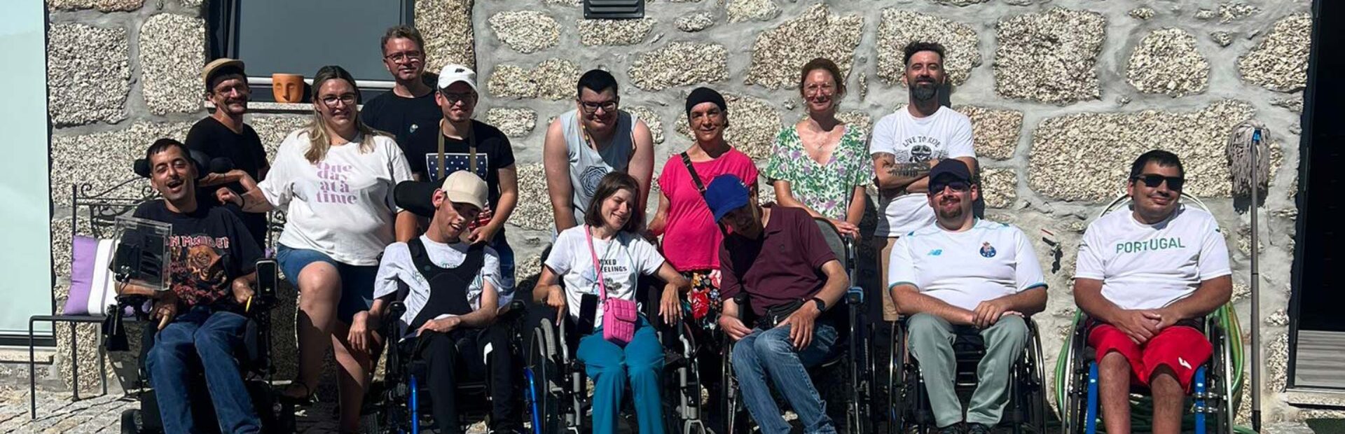 Grupo de 14 pessoas junto de um edifício construído em pedra.
