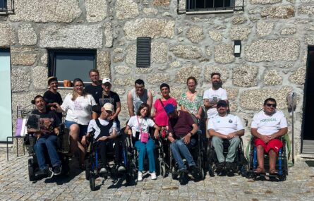 Grupo de 14 pessoas junto de um edifício construído em pedra.