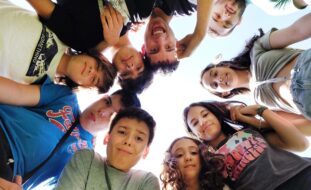 Fotografia de nove crianças e jovens que formam um círculo com os respetivos rostos.