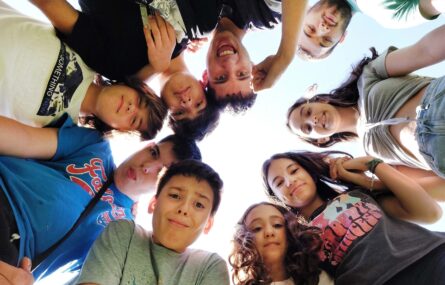 Fotografia de nove crianças e jovens que formam um círculo com os respetivos rostos.