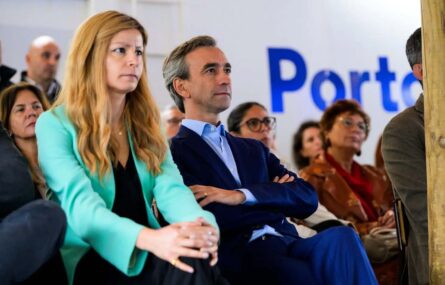 Várias pessoas sentadas a assistir a algo (não identificável na imagem). Na parede ao fundo, em letras azuis, a palavra Porto.