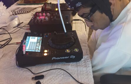 Uma pessoa utiliza equipamento eletrónico (relativo a música) pousado numa mesa.