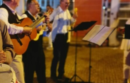 Três pessoas, na rua, com instrumentos musicais.