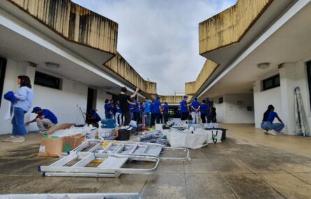 Imagem de espaço exterior da Villa Urbana. Diverso material de pintura espalhado no chão e imensas pessoas que se preparam para trabalhar.