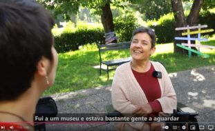 Fotograma de vídeo onde podem ver-se duas pessoas a conversar., num espaço que parece ser um jardim exterior.