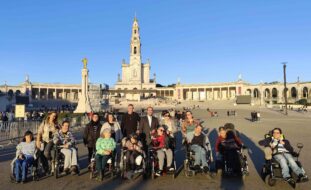 Grupo de mais de uma dezena de pessoas. Ao fundo da imagem vê-se o Santuário de Fátima.