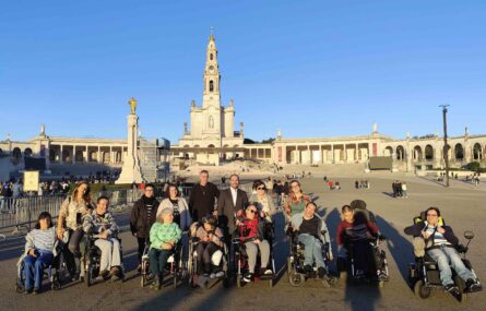 Grupo de mais de uma dezena de pessoas. Ao fundo da imagem vê-se o Santuário de Fátima.