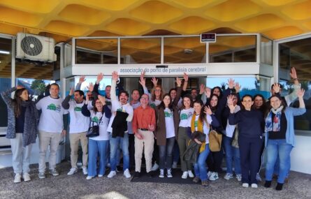 Grupo de mais de duas dezenas de pessoas junto da entrada principal da Associação do Porto de Paralisia Cerebral. A maioria das pessoas acena para a fotografia (e para o fotógrafo, ou fotógrafa).