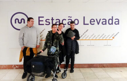 Grupo de quatro pessoas, sorridentes, junto de uma parede. Na referida parede surge a simbologia da empresa Metro do Porto, a identificação da estação na qual se encontravam (Estação da Levada) e, ainda, um mapa das restantes estações da linha de metro utilizada.