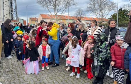 Grupo de várias dezenas de crianças e adultos em passeio por zona exterior. As crianças estão mascaradas. Os rostos identificáveis das crianças foram digitalmente desfocados.