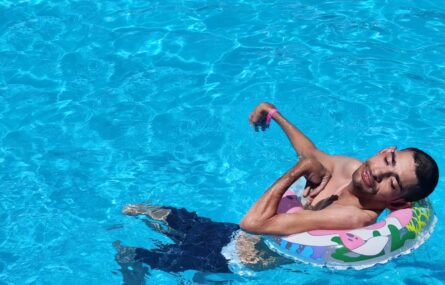 Imagem de uma pessoa dentro de uma piscina a relaxar com uma boia.