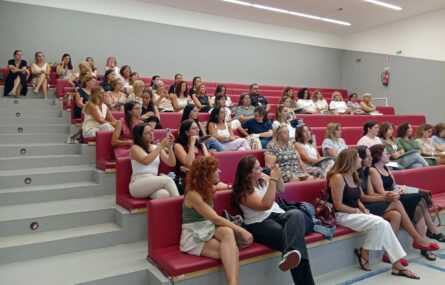 Imagem de um auditório com várias dezenas de pessoas sentadas em várias filas.