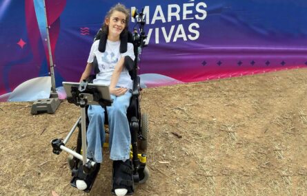 Uma pessoa, sorridente, junto de uma tela gigante com a indicação “Marés Vivas”.